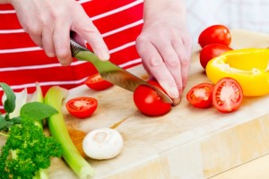 Close-up of a woman preparing vegetables on a cutting board.